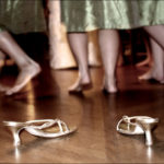 Three bridesmaids kick off their shoes to dance at a wedding reception