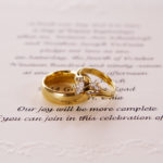 picture of a wedding invitation with wedding rings on top