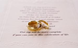 picture of a wedding invitation with wedding rings on top